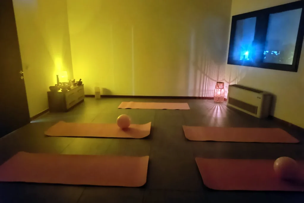 Sala con tappetini arancioni disposti a terra, illuminata da luce calda e da una lanterna