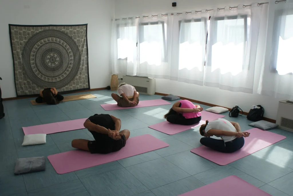 Yoga per la terza età a Treviso: un gruppo seduto sui tappetini in una piega in avanti